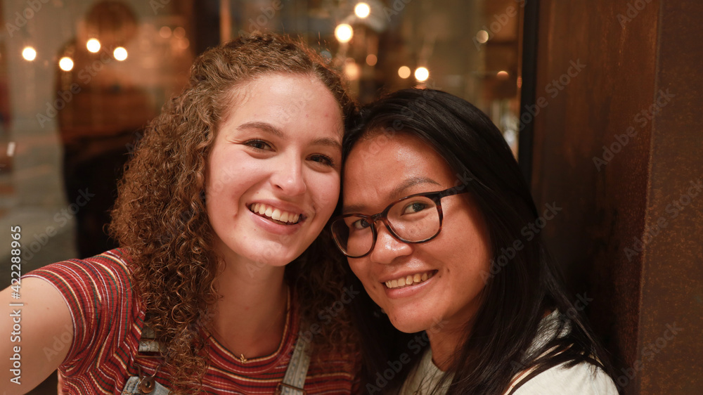 Girlfriends. Pretty multiracial female friends taking selfie with smartphone Lifestyle selfie portrait of two young positive woman taking a self photo Girlfriends. Pretty multiracial female friends taking selfie with smartphone Lifestyle selfie portrait of two young positive woman taking a self photo