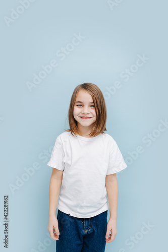 Portrait of a smiling 9 year old girl over blue background. Studio shot. © zzzdim