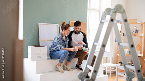 Obraz na plátně Mid adults couple with colour swatch indoors at home, relocation and diy concept
