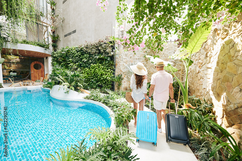 Canvastavla Young couple with suitcases walking to room of luxurious spa resort, view from t