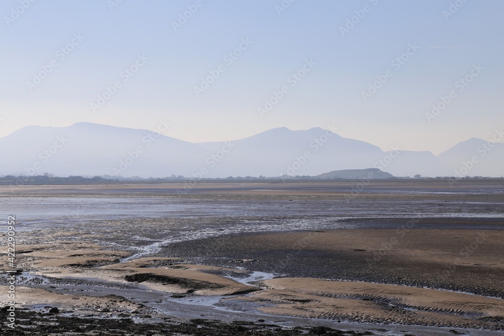 A view across the sea from Caernarfon towards the misty mountains of the Llyn Peninsula in Wales, UK.