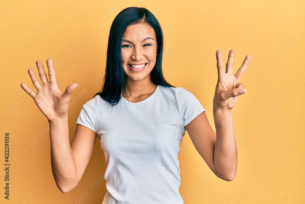 Beautiful hispanic woman wearing casual white tshirt showing and pointing up with fingers number eight while smiling confident and happy. Beautiful hispanic woman wearing casual white tshirt showing and pointing up with fingers number eight while smiling confident and happy.