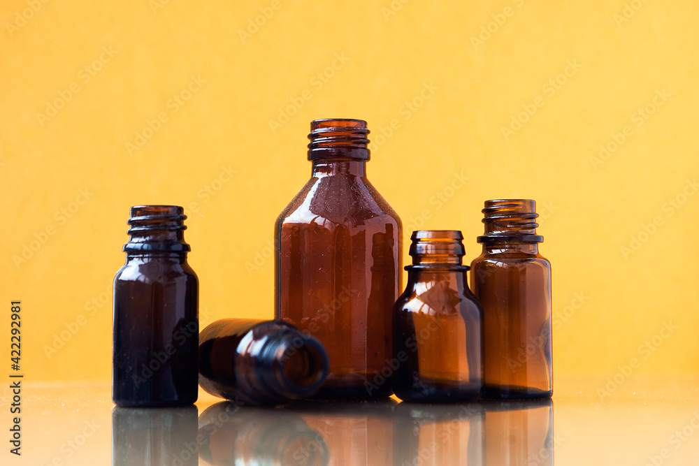 Dark brown phials on yellow background. Small empty bottles Dark brown phials on yellow background. Small empty bottles