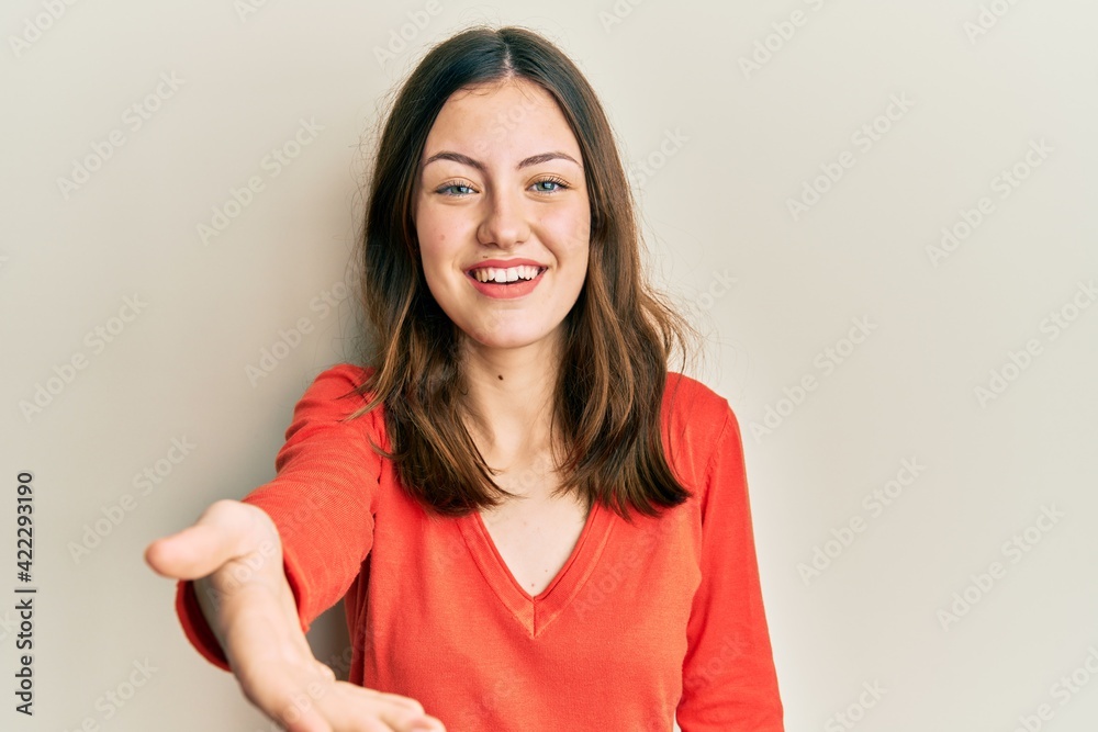 Young brunette woman wearing casual clothes smiling friendly offering handshake as greeting and welcoming. successful business. Young brunette woman wearing casual clothes smiling friendly offering handshake as greeting and welcoming. successful business.