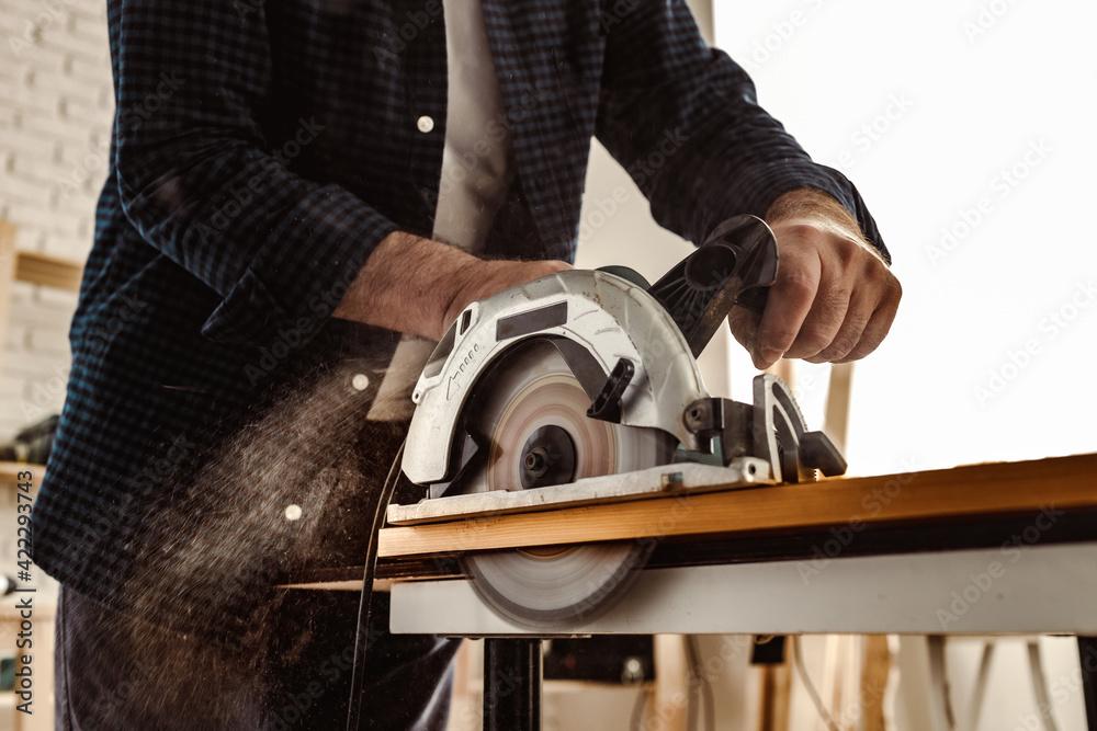 Carpenter hands cutting wood with electrical saw Carpenter hands cutting wood with electrical saw