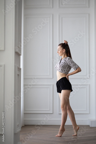 Beautiful girl doing exercises in the morning near the window, posing.
