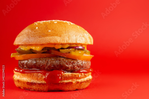 Delicious burger on a red background. Tasty fresh unhealthy burgers with cheese and two patties. Fast food  unhealthy food concept.