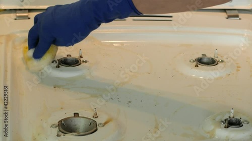 Woman clean up the mad stove. Hand in the blue gloves.