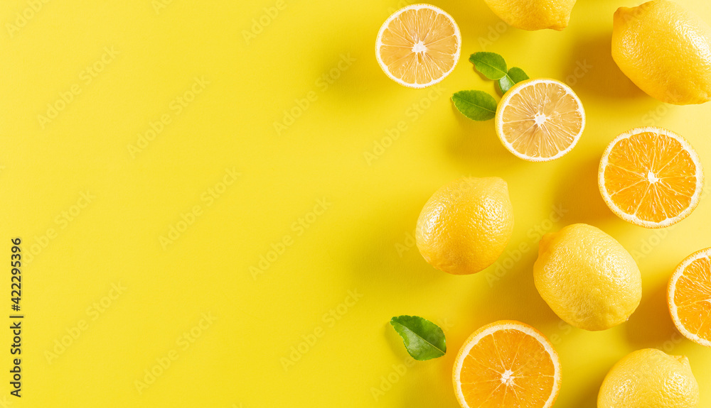Summer composition made from oranges, lemon and green leaves on pastel yellow background. Fruit minimal concept. - obrazy, fototapety, plakaty 