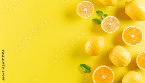 Summer composition made from oranges, lemon and green leaves on pastel yellow background. Fruit minimal concept.