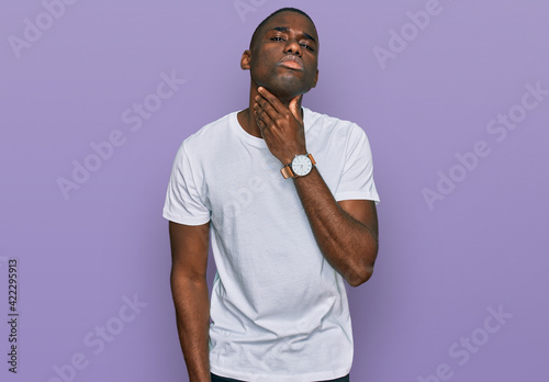 Fotografija Young african american man wearing casual white t shirt touching painful neck, s