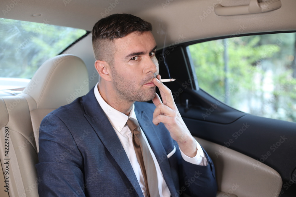 Businessman smoking in back seat Businessman smoking in back seat