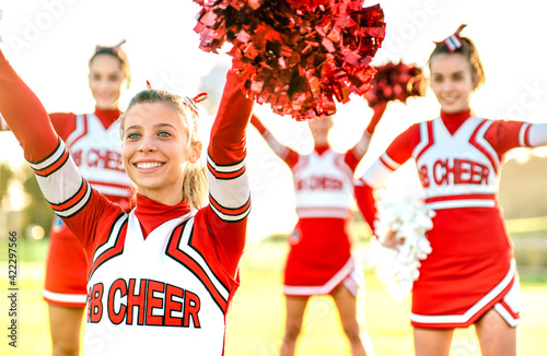 Group of female cheerleaders performing outdoors at university campus - Sport concept of cheerleading team training at high school during sunset - Warm backlight filter with focus on left girl eyes photo