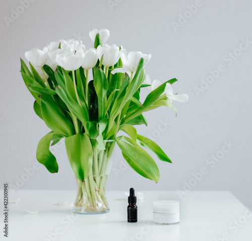 White tulips on a table with a skincare and essential oils bottles to add your own text or mockup.