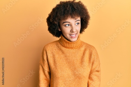 Young hispanic girl wearing wool winter sweater looking away to side with smile on face, natural expression. laughing confident. © Krakenimages.com