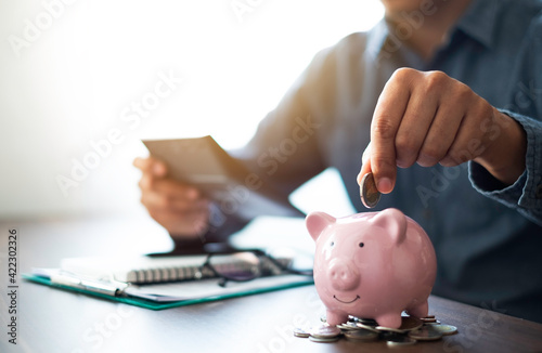Close-up image of man hand putting coins in pink piggy bank for account save money. Planning step up, saving money for future plan, retirement fund. Business investment-finance accounting concept. photo