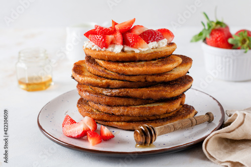 Stack of french toast with cottage cheese, honey and strawberries for breakfast. Selective focus