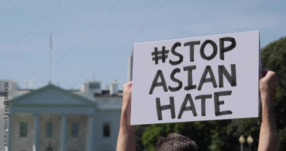 WASHINGTON, DC - Circa March, 2021 - A man waves a handmade STOP ASIAN HATE hashtag protest sign outside the White House.  	