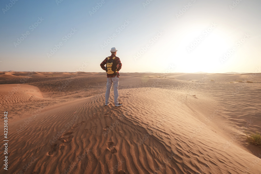 Desert adventure. Young man with backpack walking on sand dune. Dubai, United Arab Emirates Desert adventure. Young man with backpack walking on sand dune. Dubai, United Arab Emirates