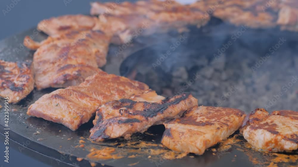 Slow motion: process of cooking fresh juicy meat steaks on brazier with hot flame at summer local food market - close up view. Outdoor cooking, gastronomy, cookery, street food concept Slow motion: process of cooking fresh juicy meat steaks on brazier with hot flame at summer local food market - close up view. Outdoor cooking, gastronomy, cookery, street food concept