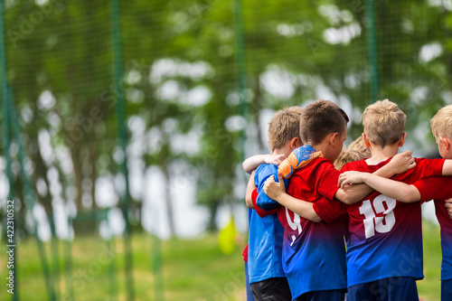 Happy Children Huddling in a Team on Sports Field. Group of School Boys Standing Together in a Circle and Motivating Themselves Before Football Match © matimix