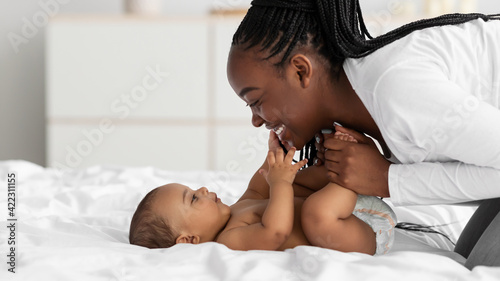 Canvas Print African American mom playing in bed with her black baby