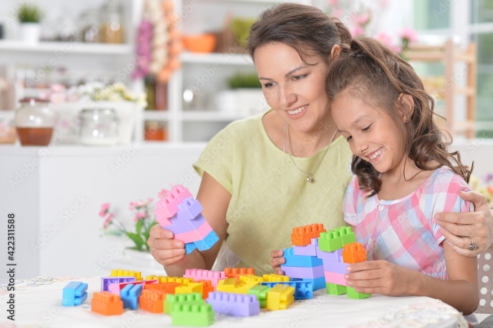 Young mother and little daughter playing blocks game