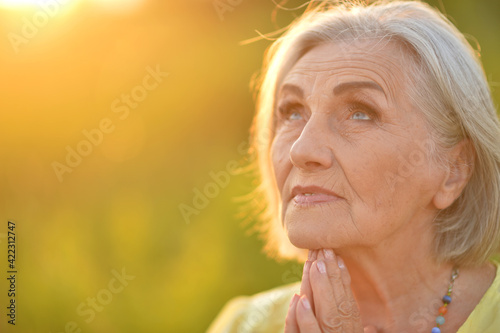 Portrait of smiling senior woman in park in summer