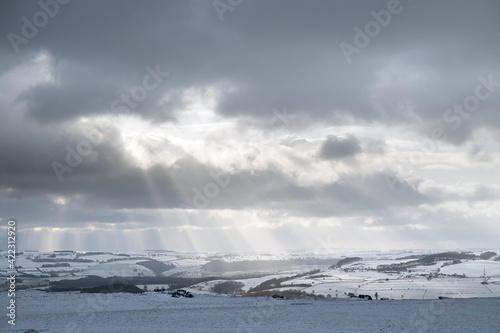 Rays of sunlight falling onto a snowy White Peak from White Edge, Peak District, UK