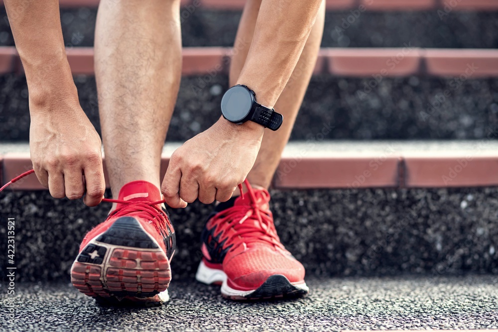 Close up, Athletics man tying shoelace on the stairs.Get ready to start exercising or running.healthy lifestyle concept. Close up, Athletics man tying shoelace on the stairs.Get ready to start exercising or running.healthy lifestyle concept.