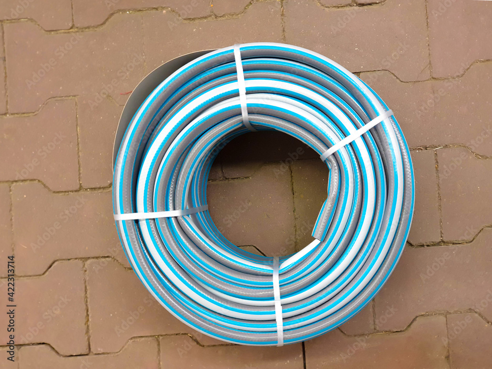 Garden irrigation twisted hose on tile. Rubber watering hose twisted, top view. Garden irrigation twisted hose on tile. Rubber watering hose twisted, top view.