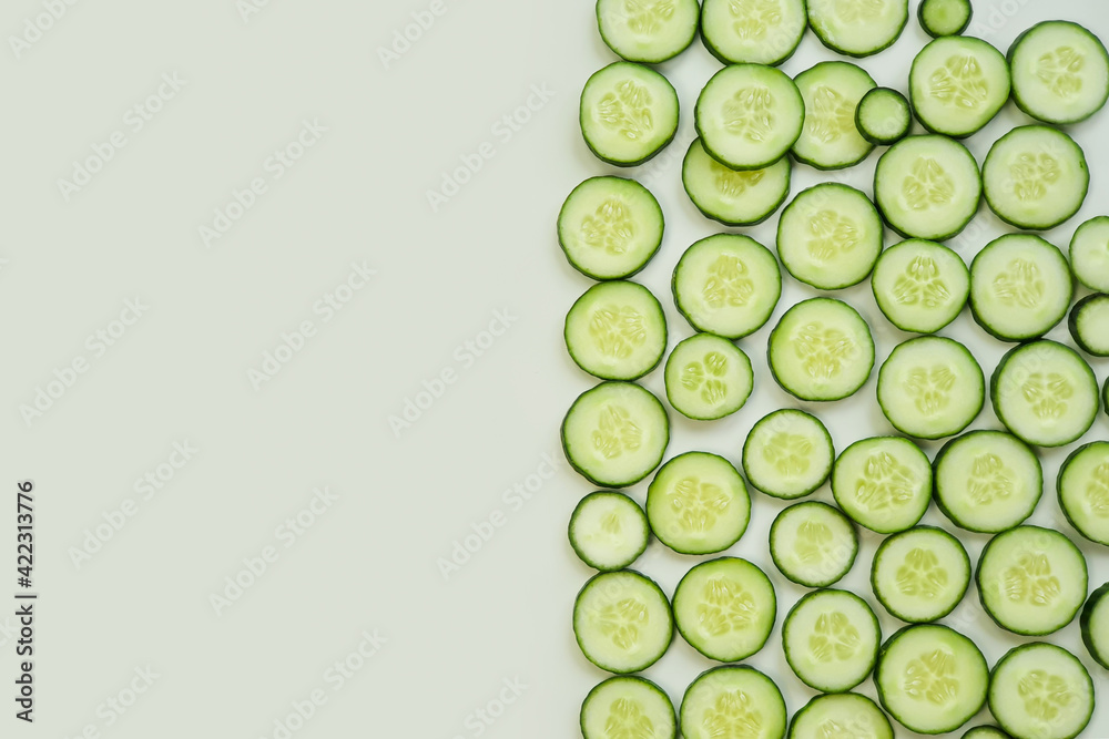 Top view of fresh sliced cucumbers on green background with copy space.