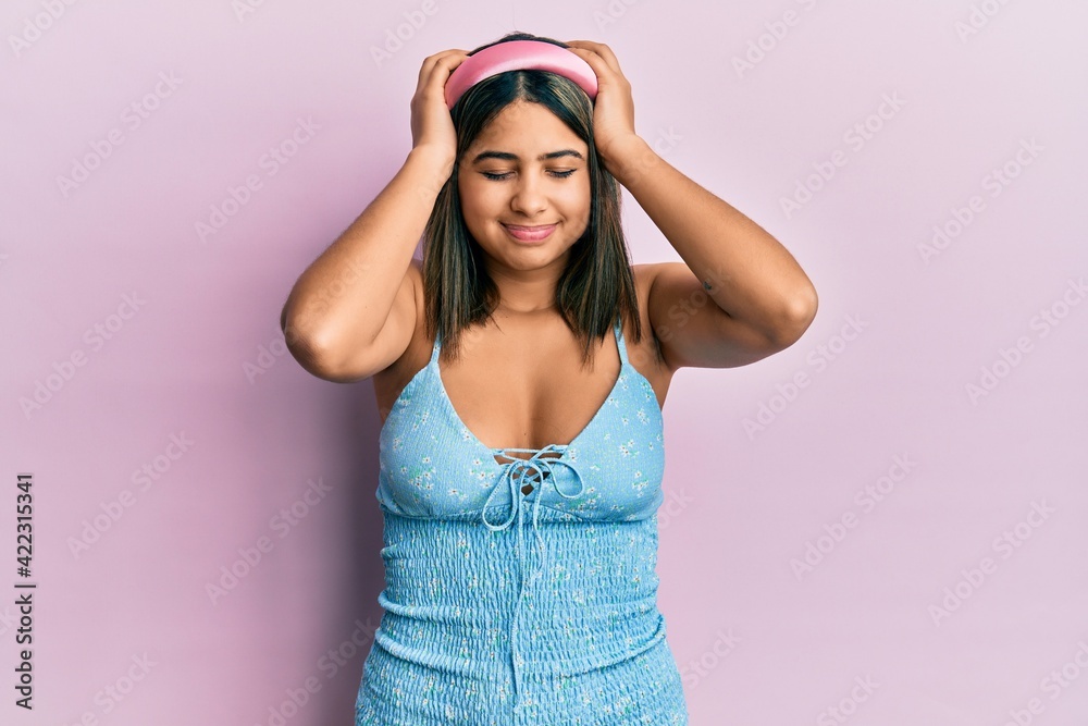 Young latin woman wearing summer clothes suffering from headache desperate and stressed because pain and migraine. hands on head. Young latin woman wearing summer clothes suffering from headache desperate and stressed because pain and migraine. hands on head.