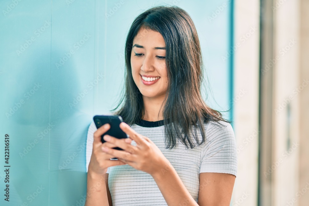Young hispanic woman smiling happy using smartphone at the city. Young hispanic woman smiling happy using smartphone at the city.