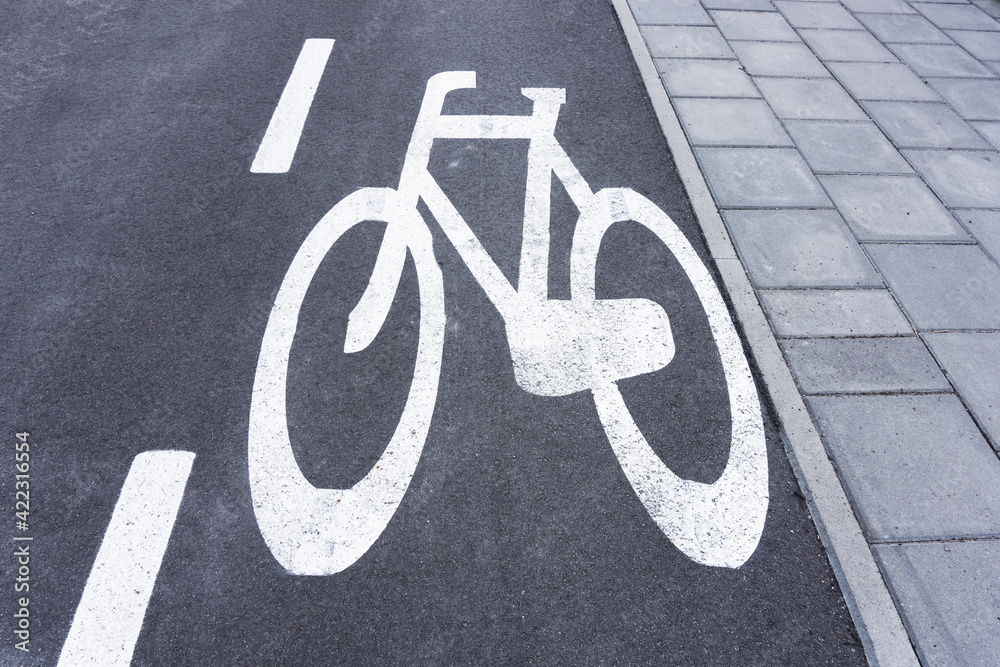 Obraz premium Bicycle lane background. Asphalt road for bikes. White paint bicycle painted on street. Pavement and bicycle lane. Walking and cycling path.