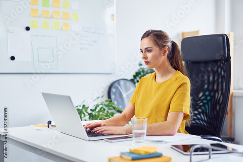 Young businesswoman working on laptop in small office