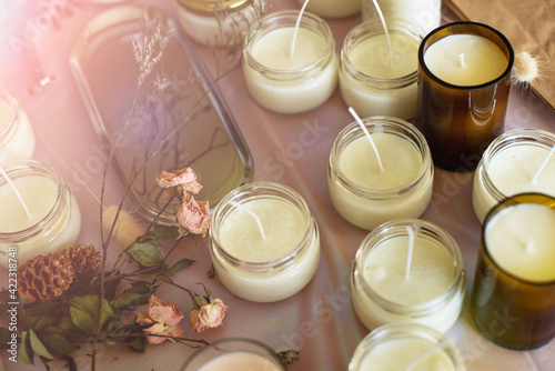 Soy Candles poured into recycled bottles and jars. Many soy wax candles together on store or workshop background. . Ecological and vegan business.