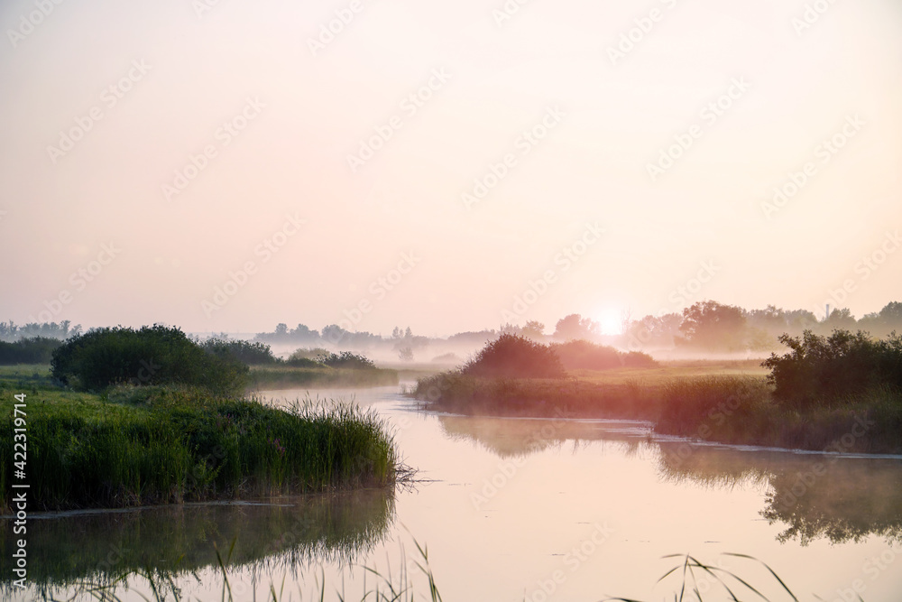 Sunrise in a light fog on a small river