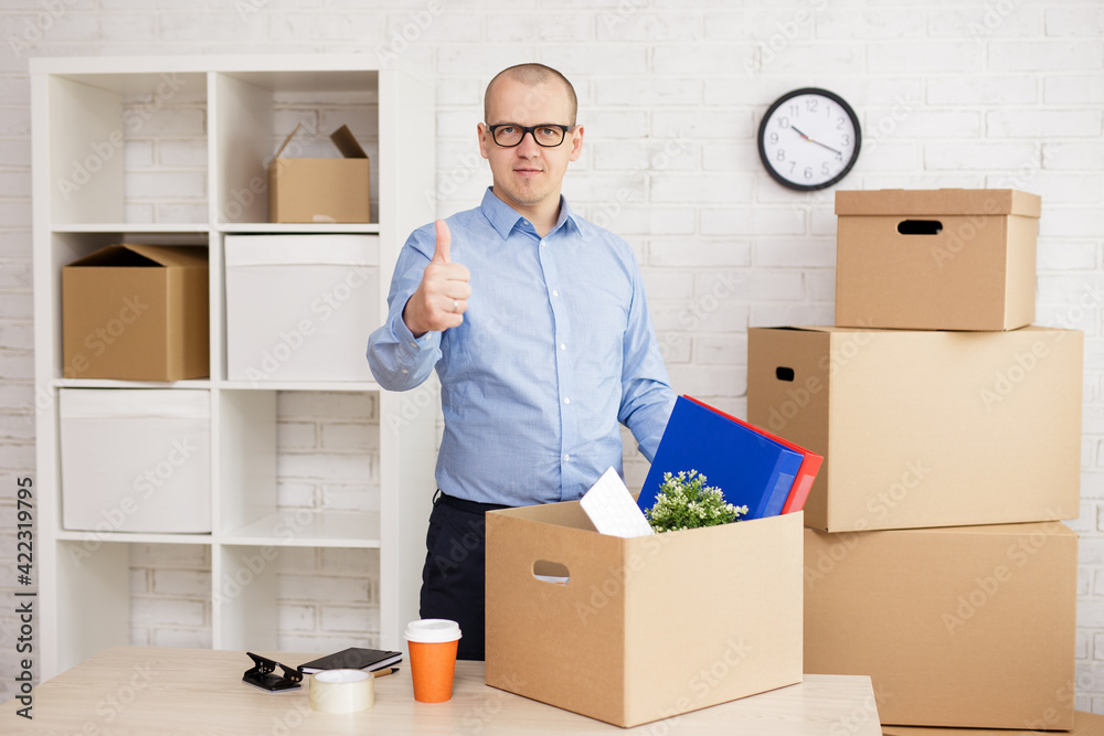 man showing thumbs up gesture in the office with cardboard boxes man showing thumbs up gesture in the office with cardboard boxes