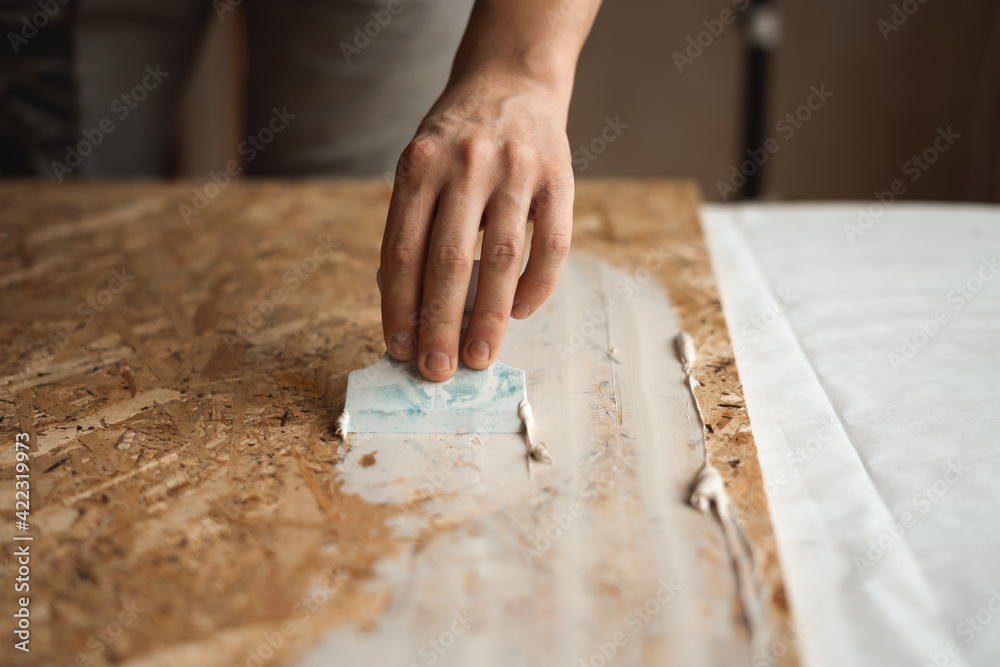 Hand applies the putty with a spatula Hand applies the putty with a spatula