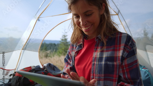 Girl shopping online on digital tablet in tent with mountains on background