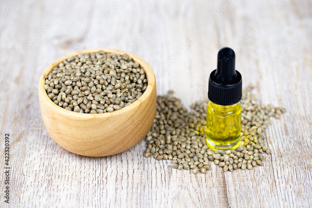 Cannabis seeds in a wooden bowl and hemp oil. Concept of extracting hemp leaves into oil. For natural remedies, natural herbal medicine. Alternative medicine. Cannabis seeds in a wooden bowl and hemp oil. Concept of extracting hemp leaves into oil. For natural remedies, natural herbal medicine. Alternative medicine.