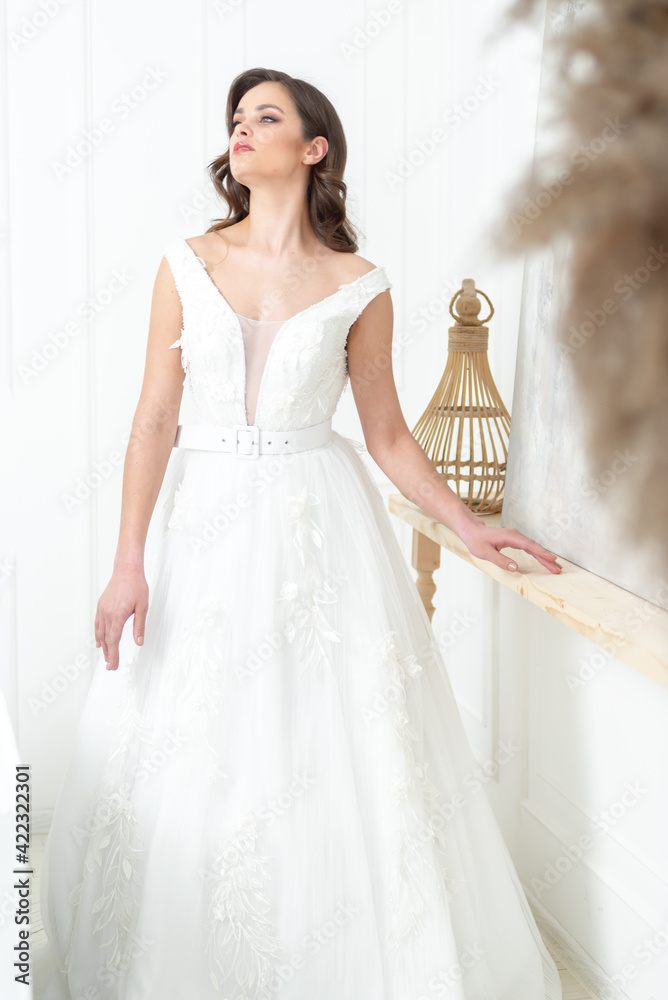 Bride in beautiful dress standing indoors interior at home. Trendy wedding style shot. Wedding makeup and hairstyle. Beautiful Bride in the morning. Bride in beautiful dress standing indoors interior at home. Trendy wedding style shot. Wedding makeup and hairstyle. Beautiful Bride in the morning.
