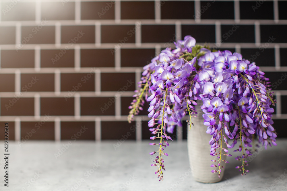 Fresh picked vibrant purple wisteria in a gray vase from a garden in the spring. Fresh picked vibrant purple wisteria in a gray vase from a garden in the spring.