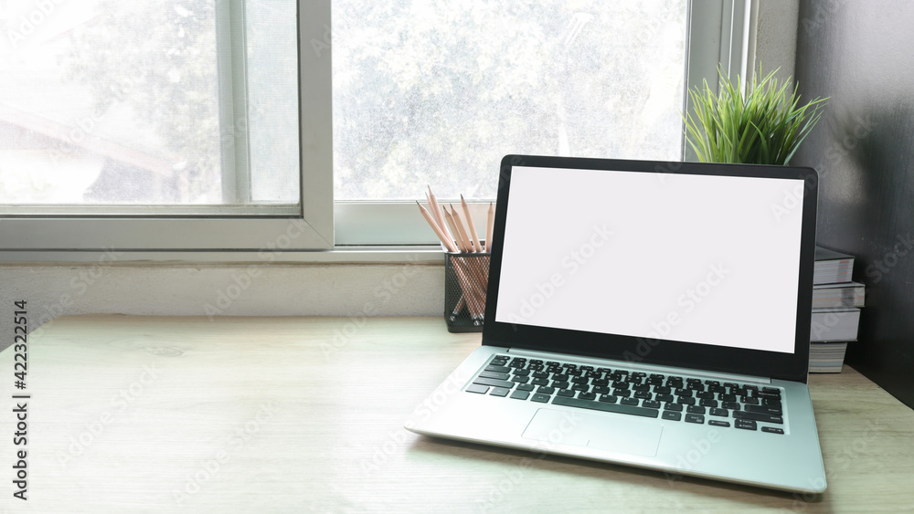 Fototapeta premium Laptop computer with white blank screen on desk in workspace and copy space concept