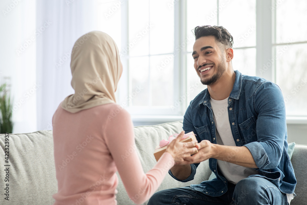 Handsome middle-eastern guy giving his girlfriend present Handsome middle-eastern guy giving his girlfriend present