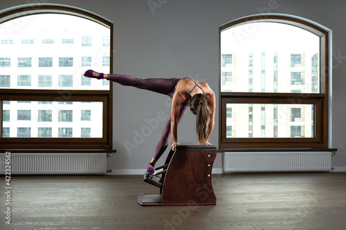 Beautiful woman doing pilates exercise, training on barrels. Fitness concept, special fitness equipment, healthy lifestyle, plastic. Copy space, sport banner for advertising