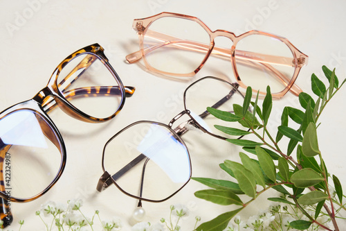 several fashionable glasses and flowers on a beige background copy space top view