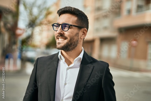 Young hispanic businessman smiling happy standing at the city.