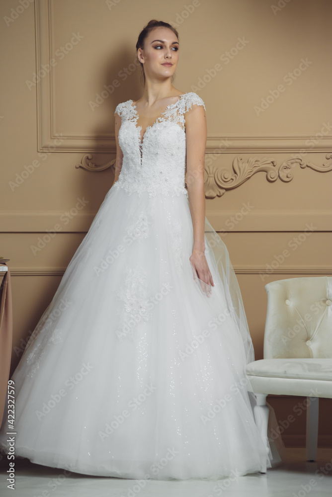 Happy bride in luxury sparkly wedding dress posing in studio on brown background. Marriage concept. Happy bride in luxury sparkly wedding dress posing in studio on brown background. Marriage concept.